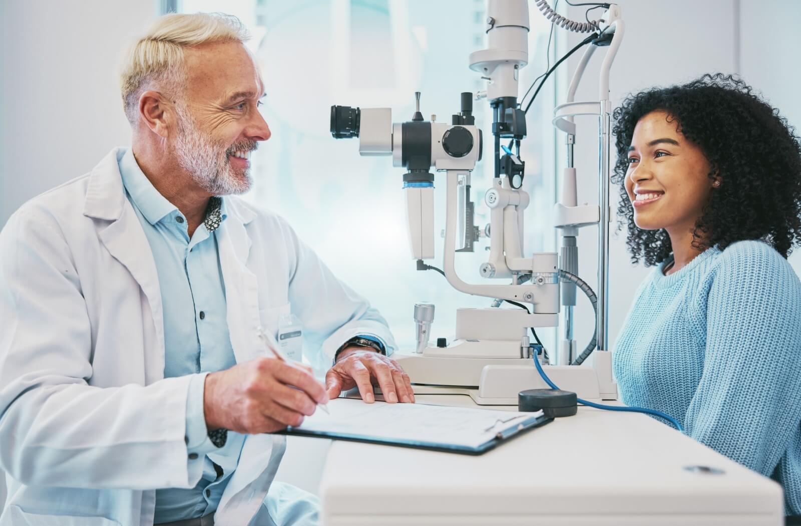 An eye doctor discusses his patient's symptoms and medical history during a comprehensive eye examination in order to offer her tailored advice on the benefits of glasses for her tired eyes.