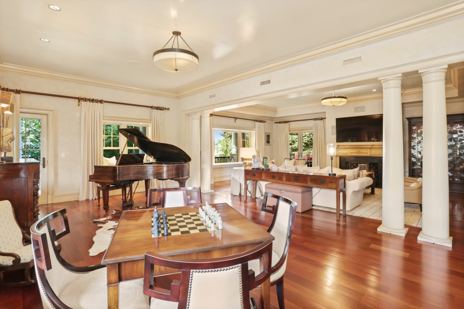 Classically styled music and game room features a blend of creamy white walls juxtaposed with warm mahogany toned furnishings including a baby grand piano and chess-board games table