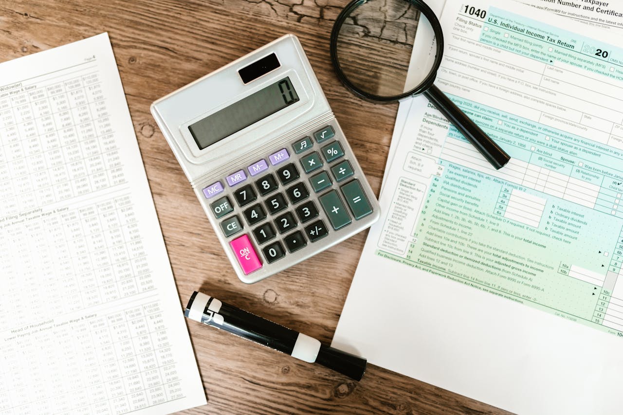 A desk cluttered with tax forms and a calculator, ready for tax season calculations and paperwork organization.