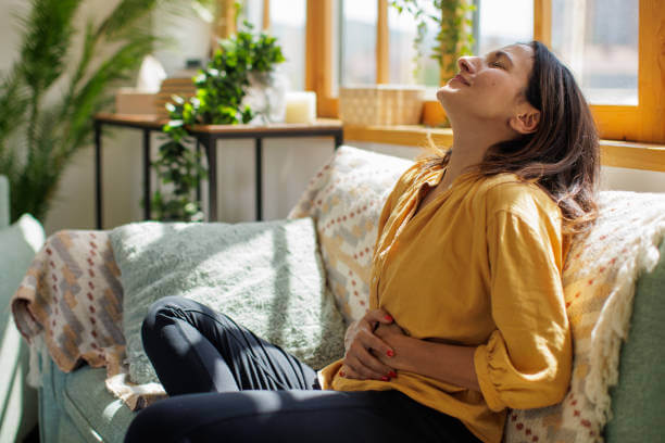 Smiling woman gently holding her stomach in relief after using effective digestive health supplements.