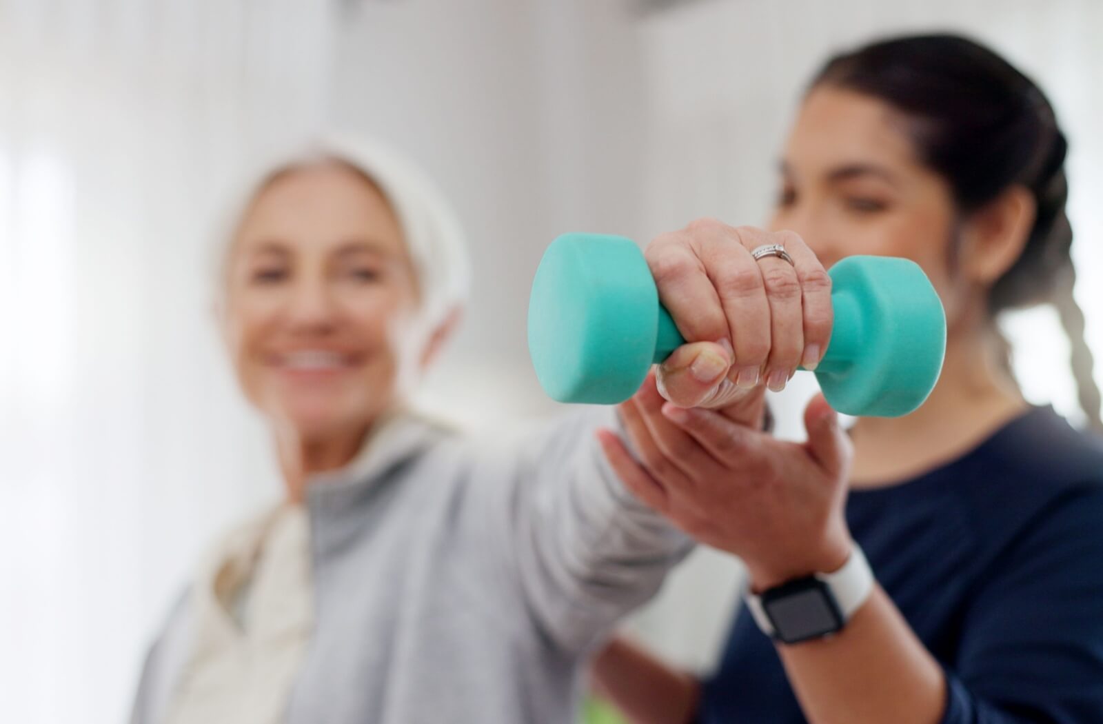 A senior lifts weights during a physiotherapy session to improve their strength alongside their mobility.