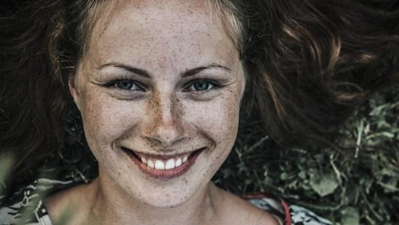 bilden visar en person med handen framför ansiktet, målad i flera olika klara färger.