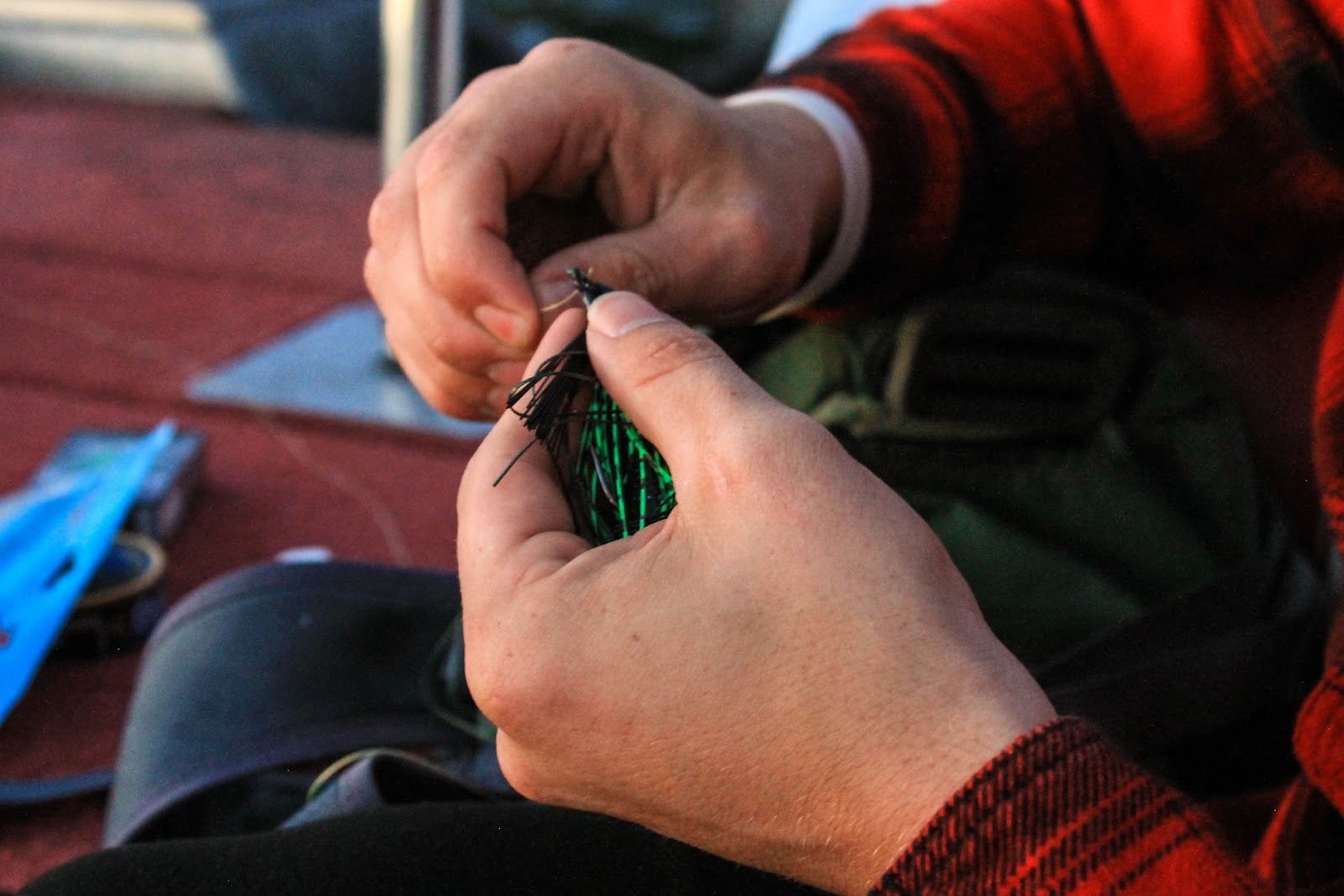 Man harnessing hook to fishing lure.
