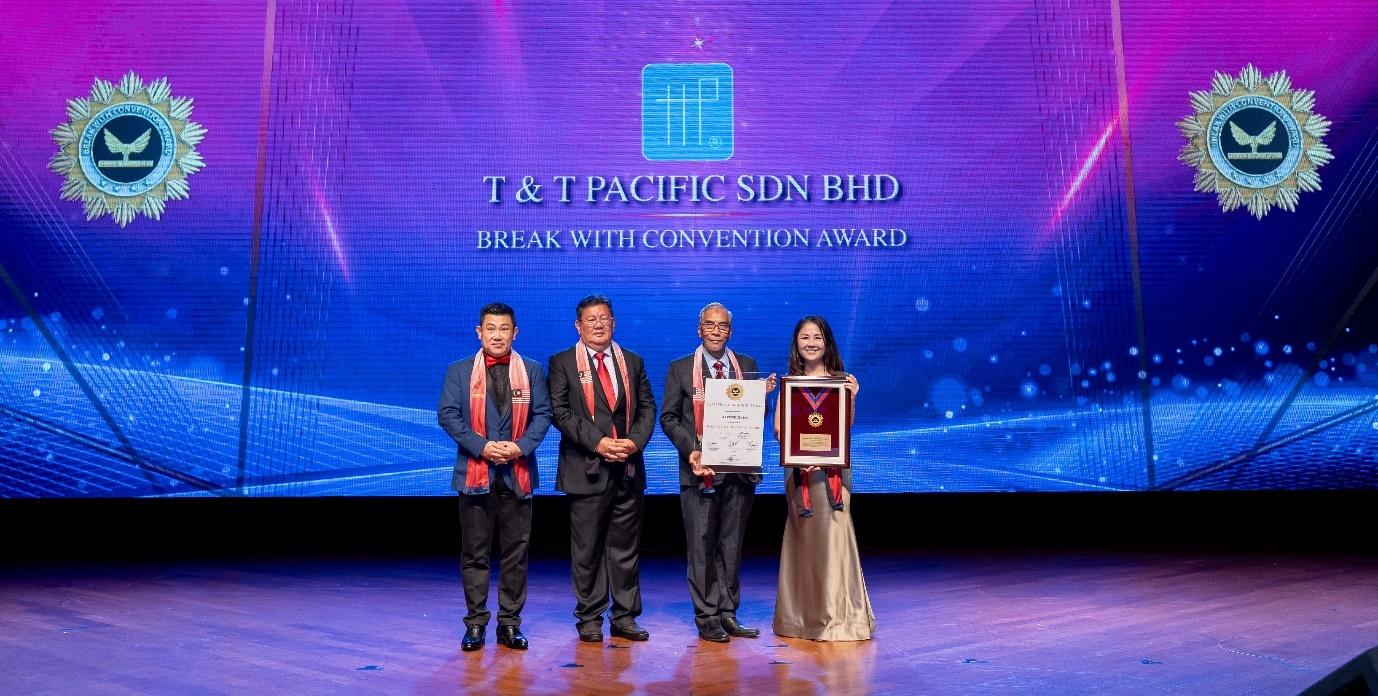 A group of people standing on a stage holding a plaque

Description automatically generated