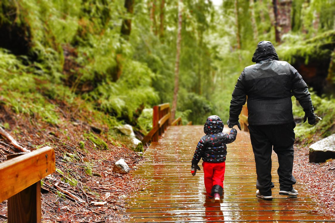 A person and child walking on a wooden bridgeAI-generated content may be incorrect.