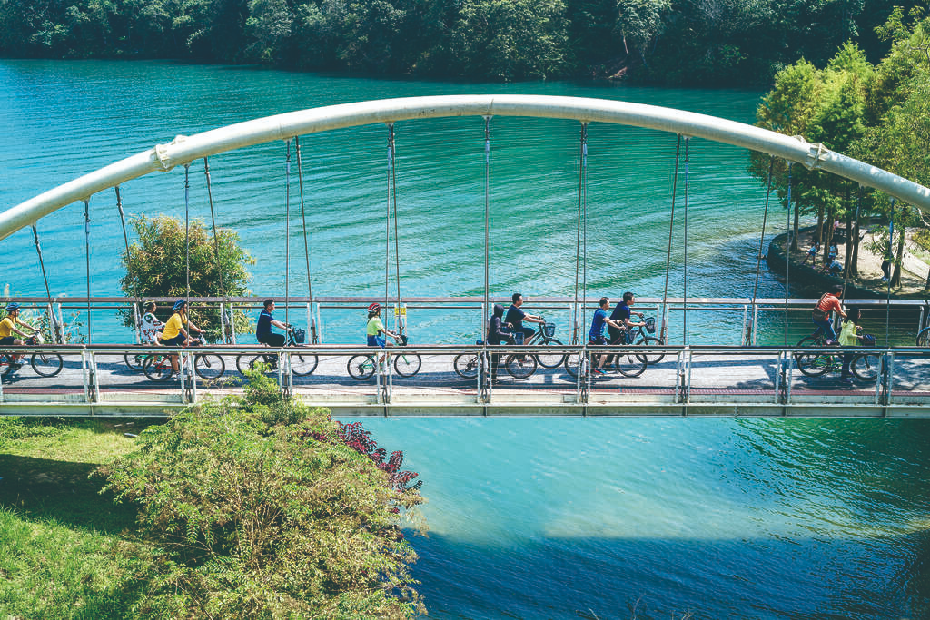 Cyclists riding along the edge of Sun Moon Lake with scenic views