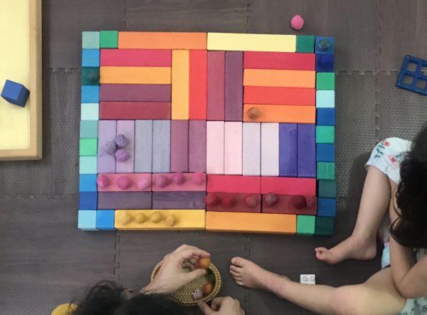 Children lining blocks to create a symmetry pattern in  a rectangular structure. Here children understand the concept of symmetry and squares of numbers. 
