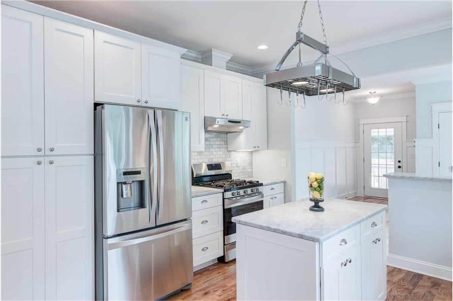 A stainless steel pot rack hangs over the center island.