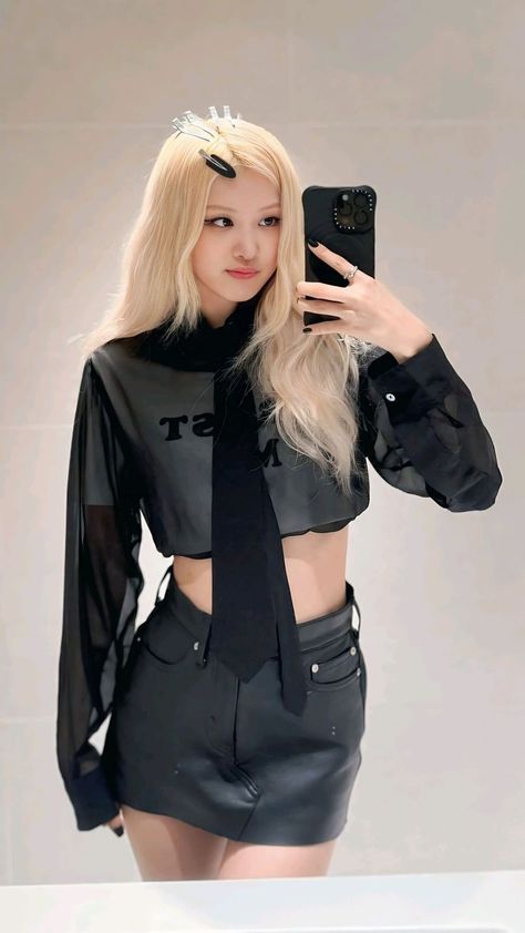 This contains an image of Blackpink Rose taking a selfie in front of a mirror wearing a black shirt and skirt