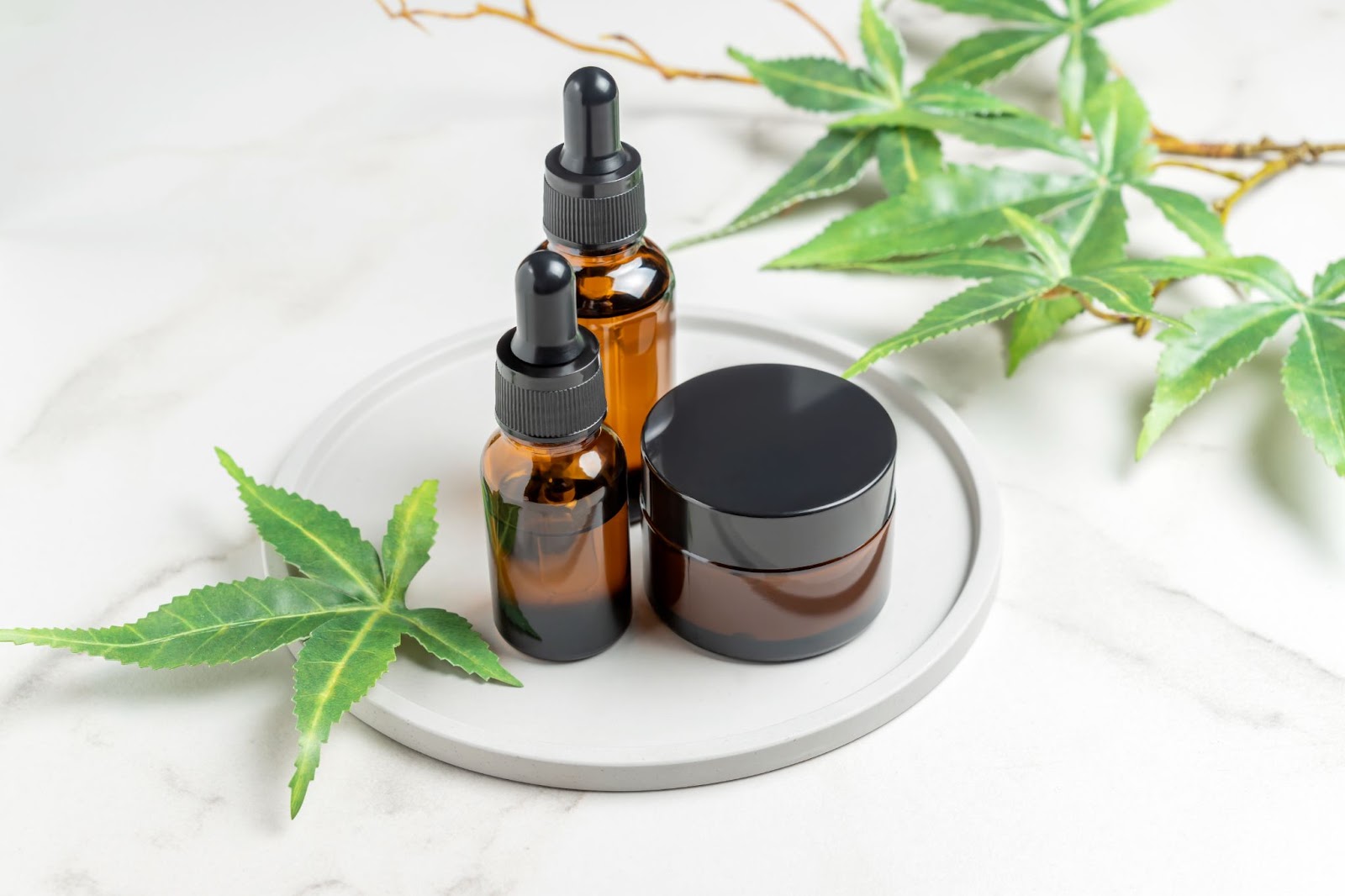 CBD products near hemp leaves on ceramic dish