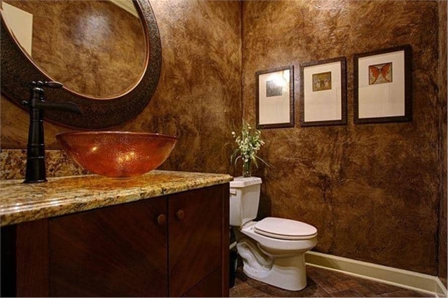 Powder room with a vessel sink vanity, a toilet, and framed artworks adorning the textured walls.