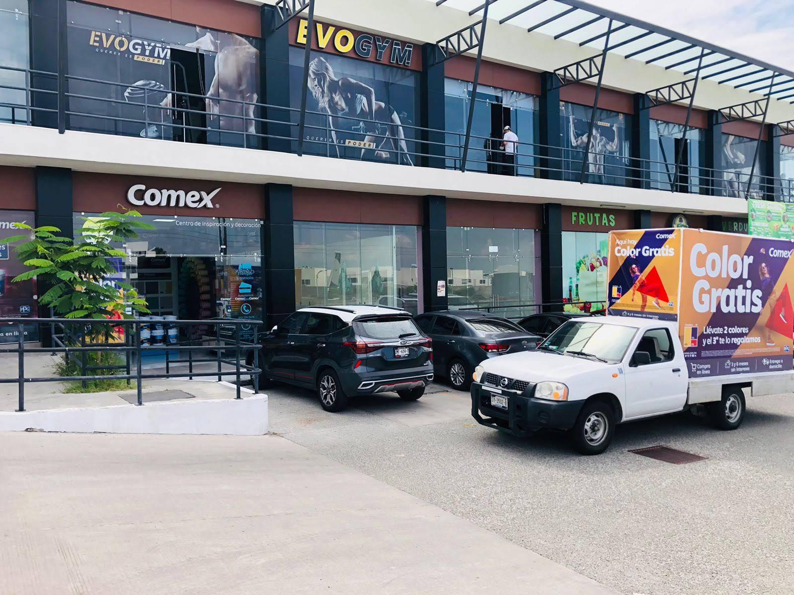 Edificio con letrero en frente y tienda al lado de un coche

Descripción generada automáticamente con confianza media
