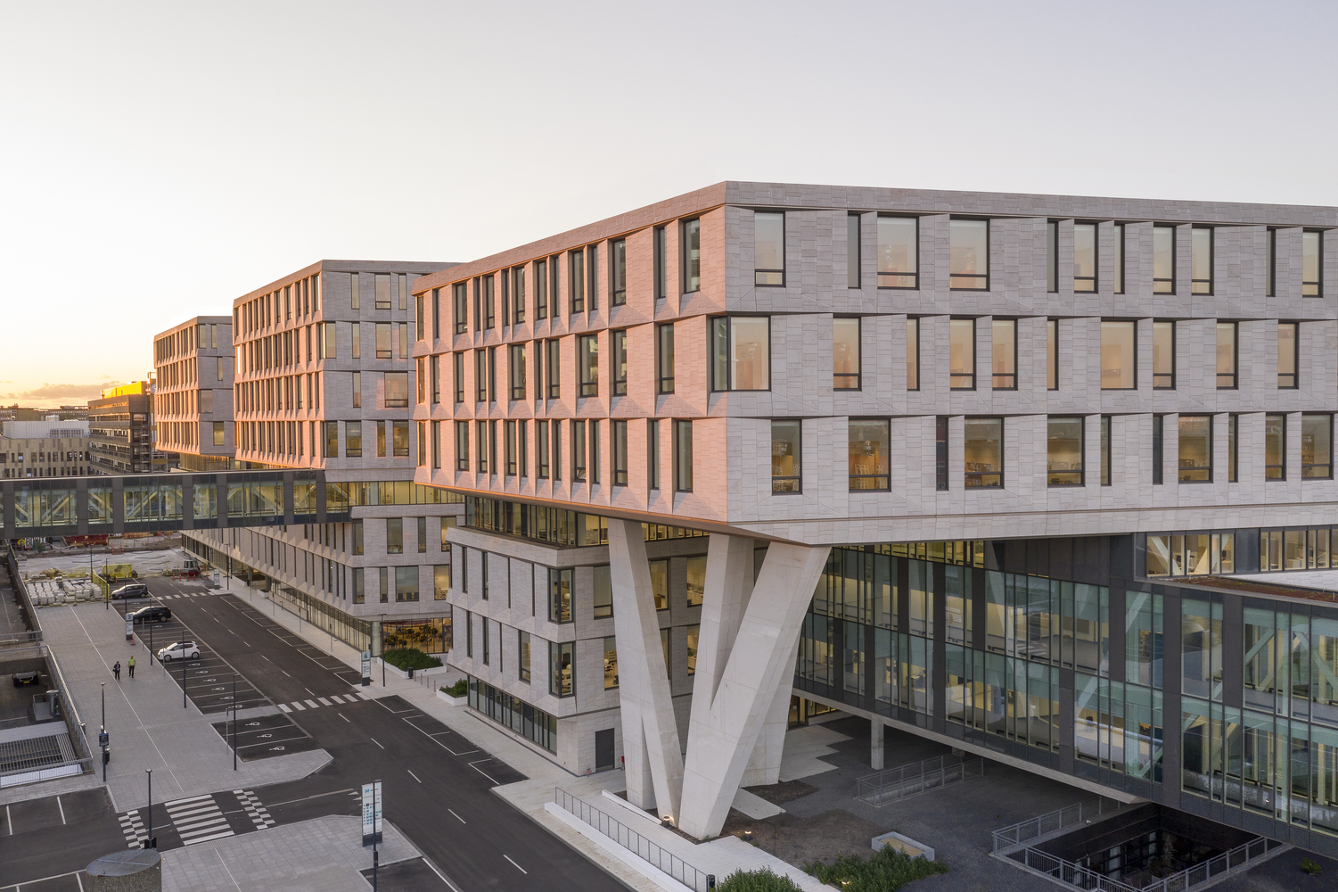 A modern hospital building with large windows and cantilevered sections, connected by glass skywalks.