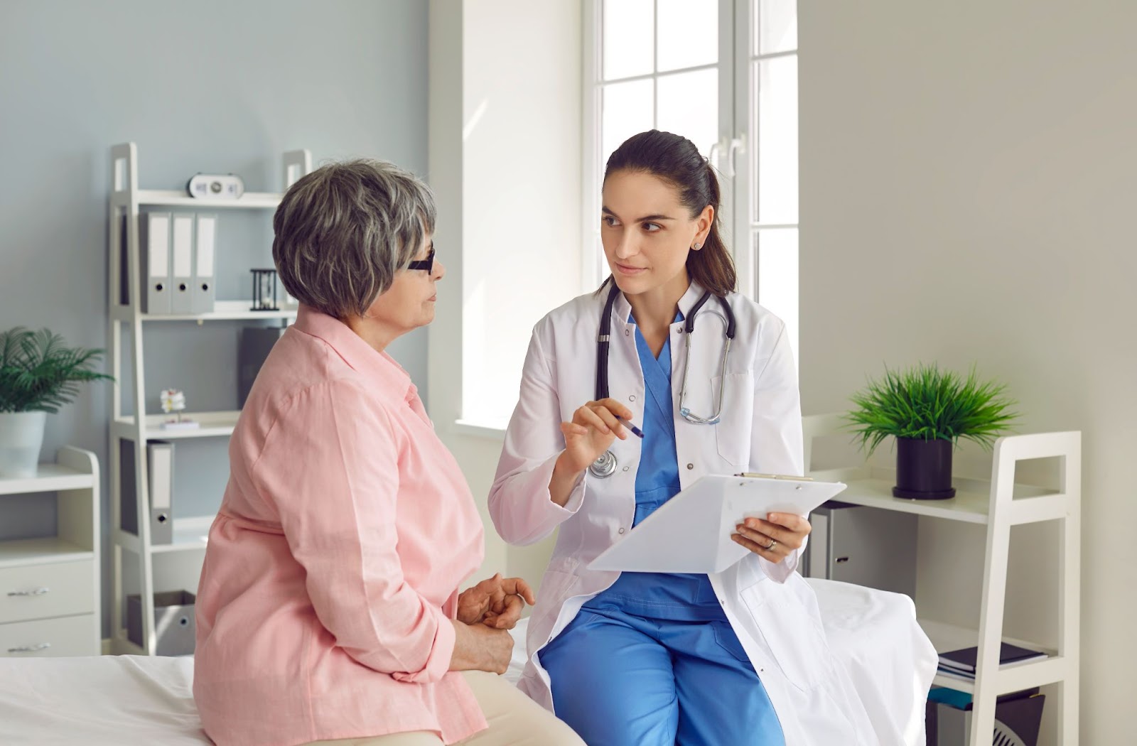 Female discusses a senior woman's medical chart with her.