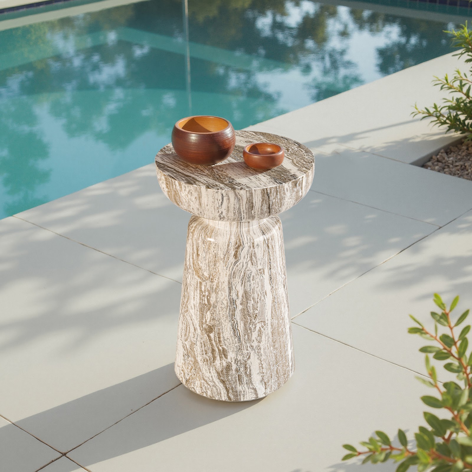 Grover Outdoor Faux Marble Chalice Side Table with a round top and tapered base in a travertine-style finish, set beside a pool—ideal for adding sculptural charm and weather-resistant function to upscale outdoor lounging spaces.