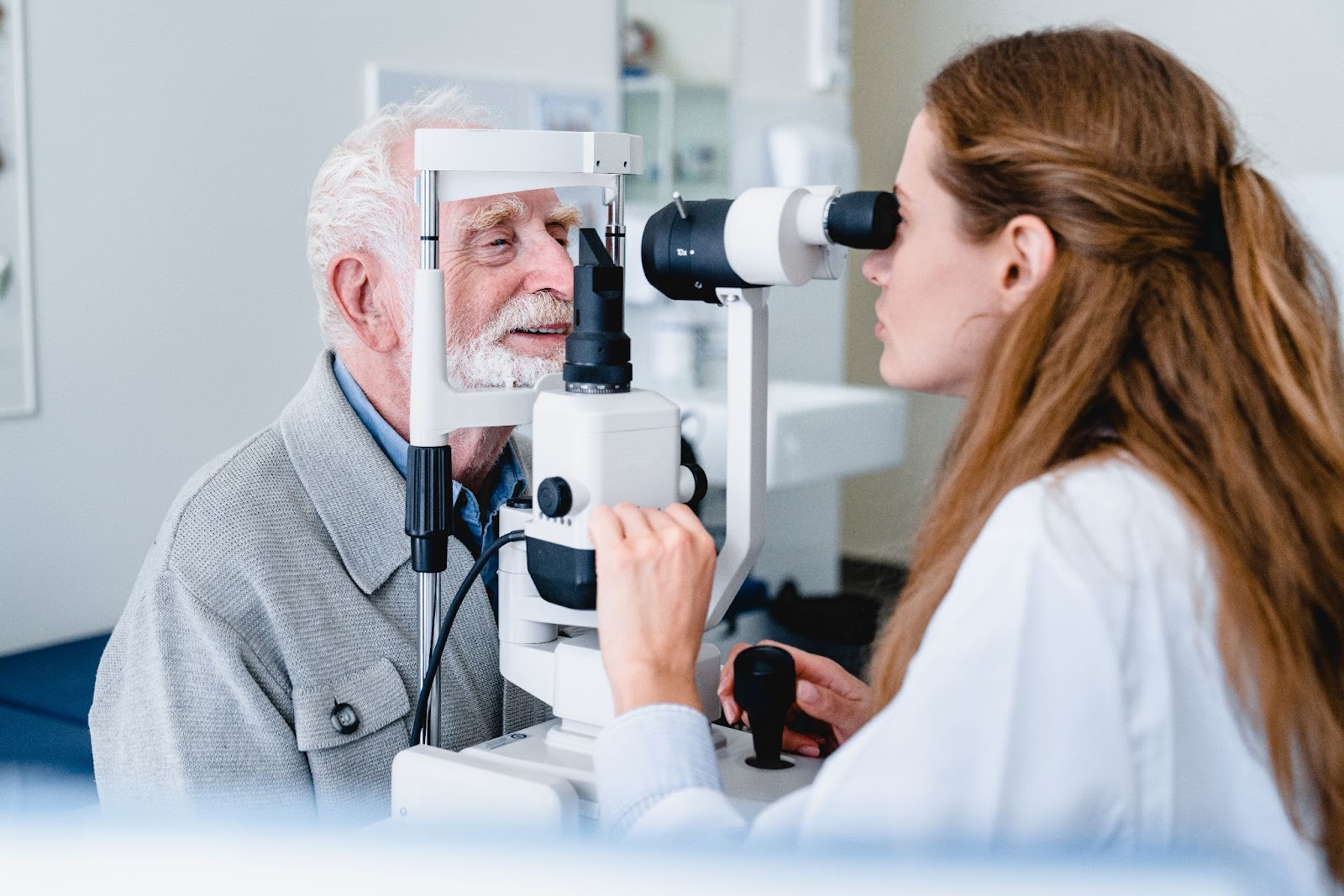 A smiling senior man having his eyes checked for cataracts by a female optometrist.