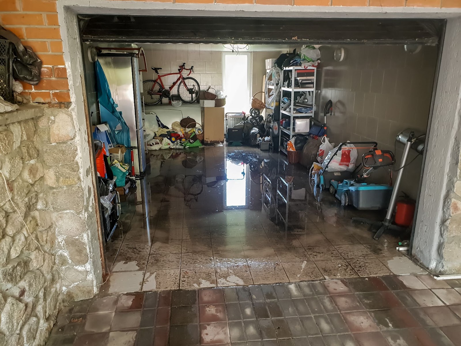 A flooded garage with wet floor and debris after heavy rain.