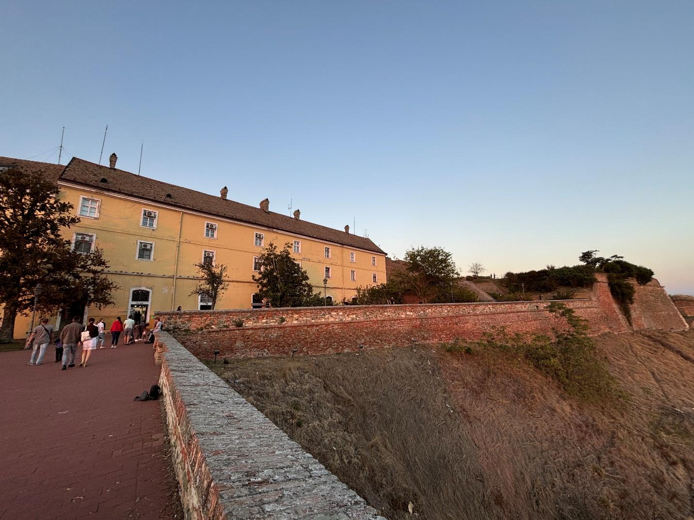 A group of people walking on a path next to a building AI-generated content may be incorrect.
