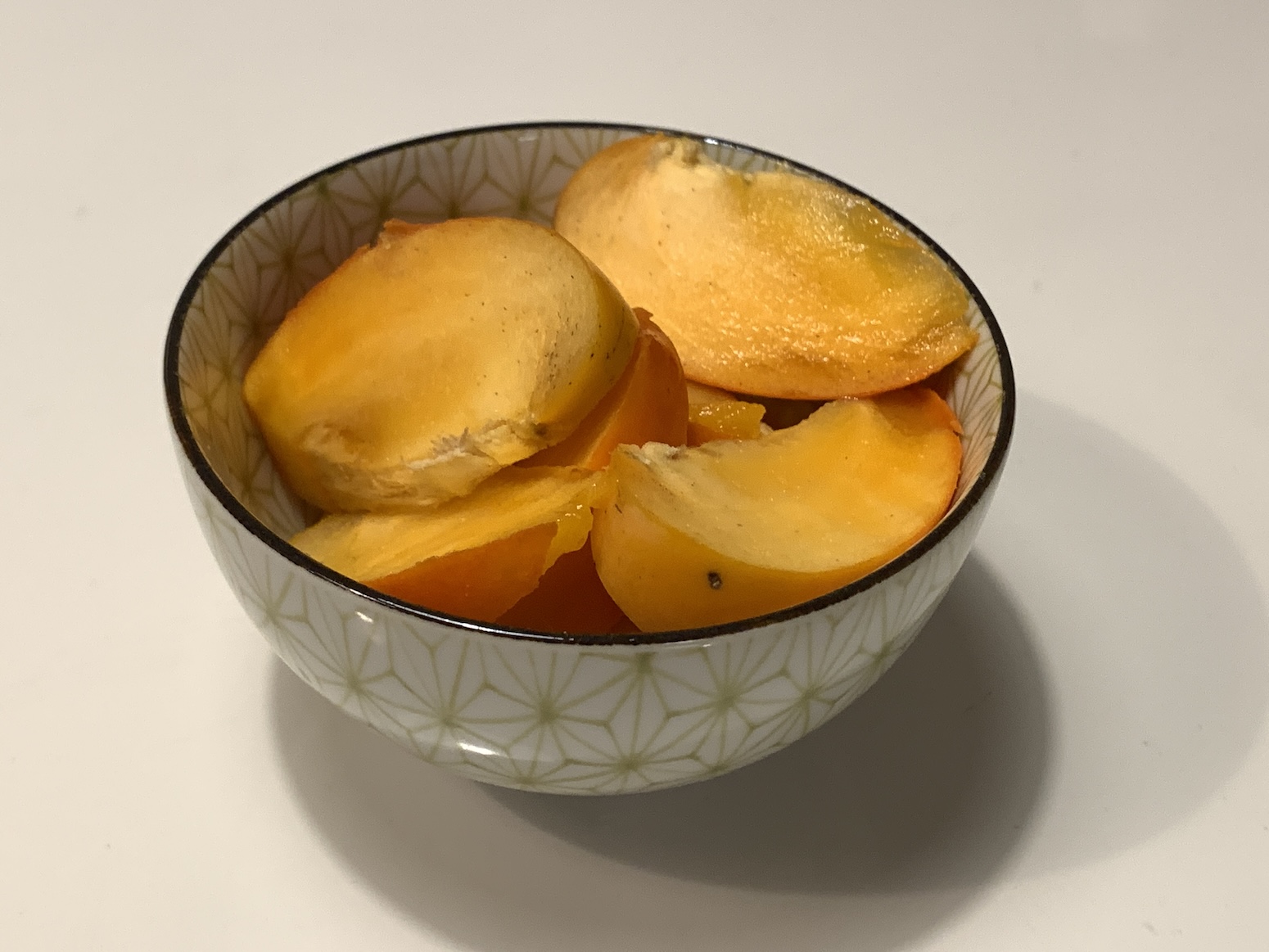 Persimmon cut up and placed in a lovely star-patterned serving bowl.