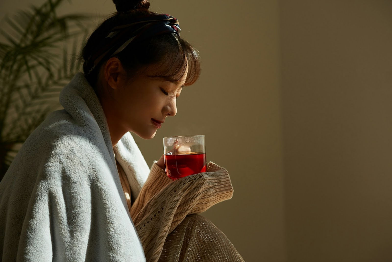 A woman wrapped in a blanket enjoying a relaxing cup of tea