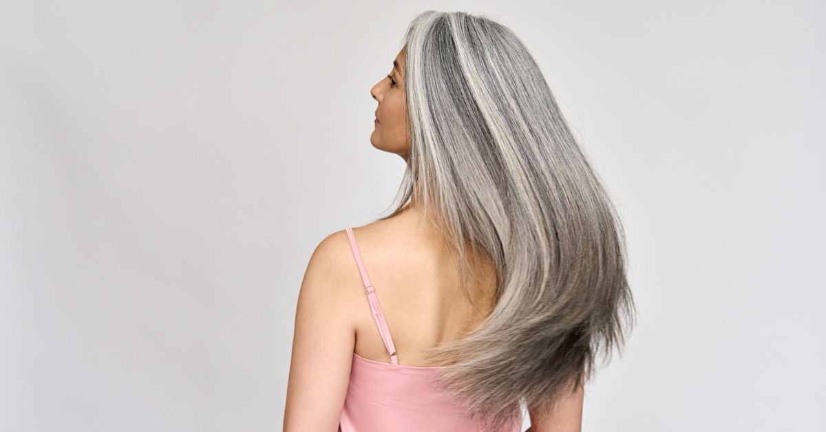 A woman with long, straight hair showcasing a stylish gray blending technique for long hair.
