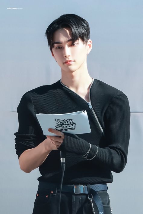 SEUNGHAN RIIZE wearing a black long sleeve shirt and a black trouser holding a book