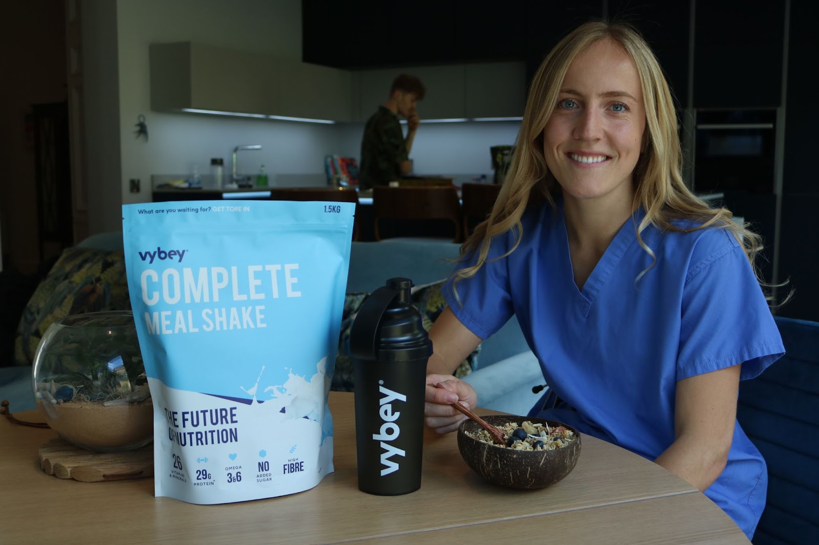 woman smiling eating her vybey complete meal shake in a nutritious smoothie bowl