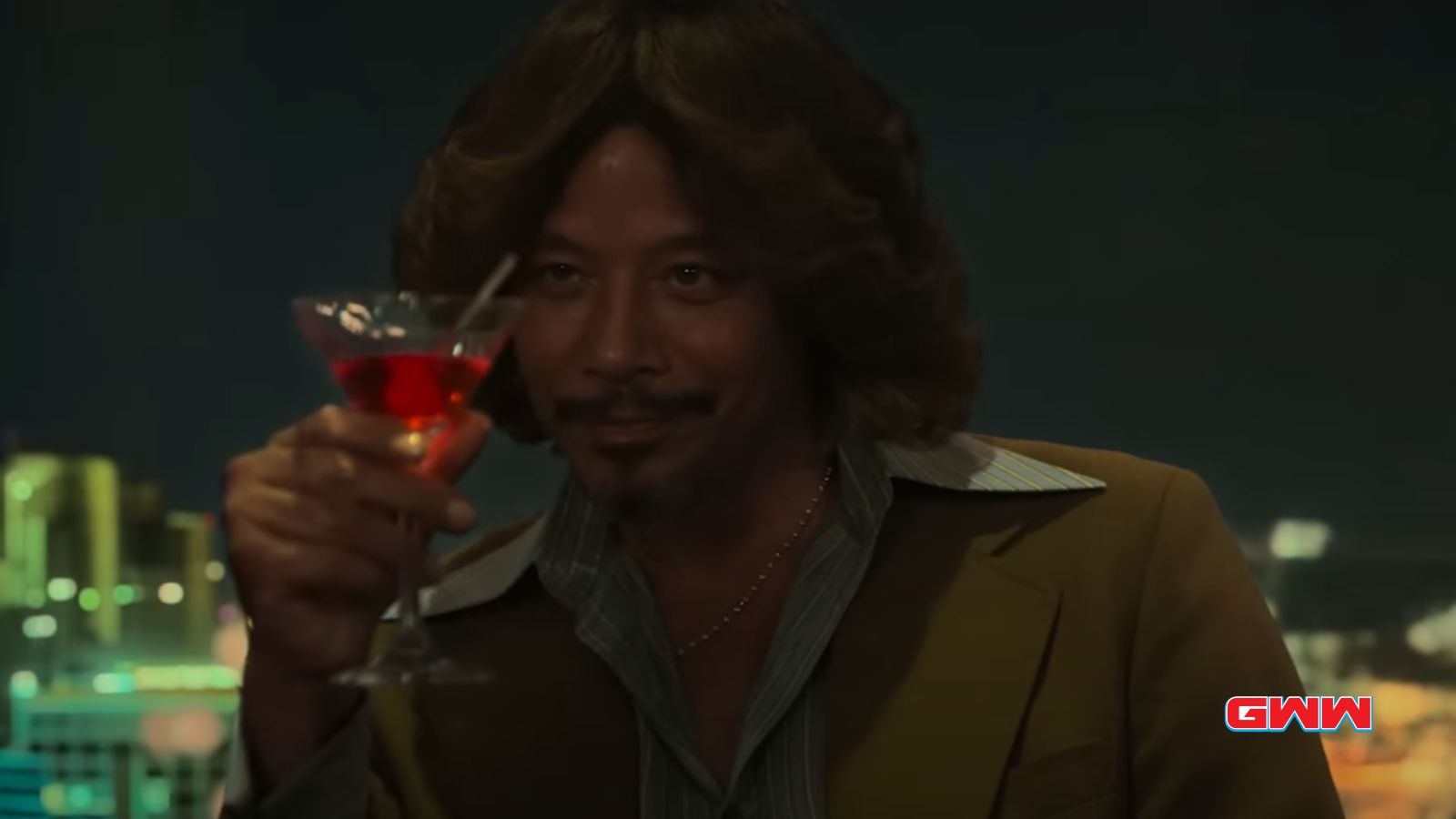 Cadillac Richie with long hair and mustache raising a cocktail glass, city lights background.