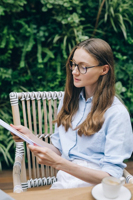 woman outdoor reading a book with her glasses on