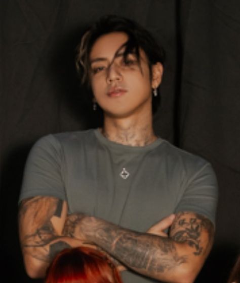 This contain DPR Ian with tattoos standing in front of a black background holding his arms crossed