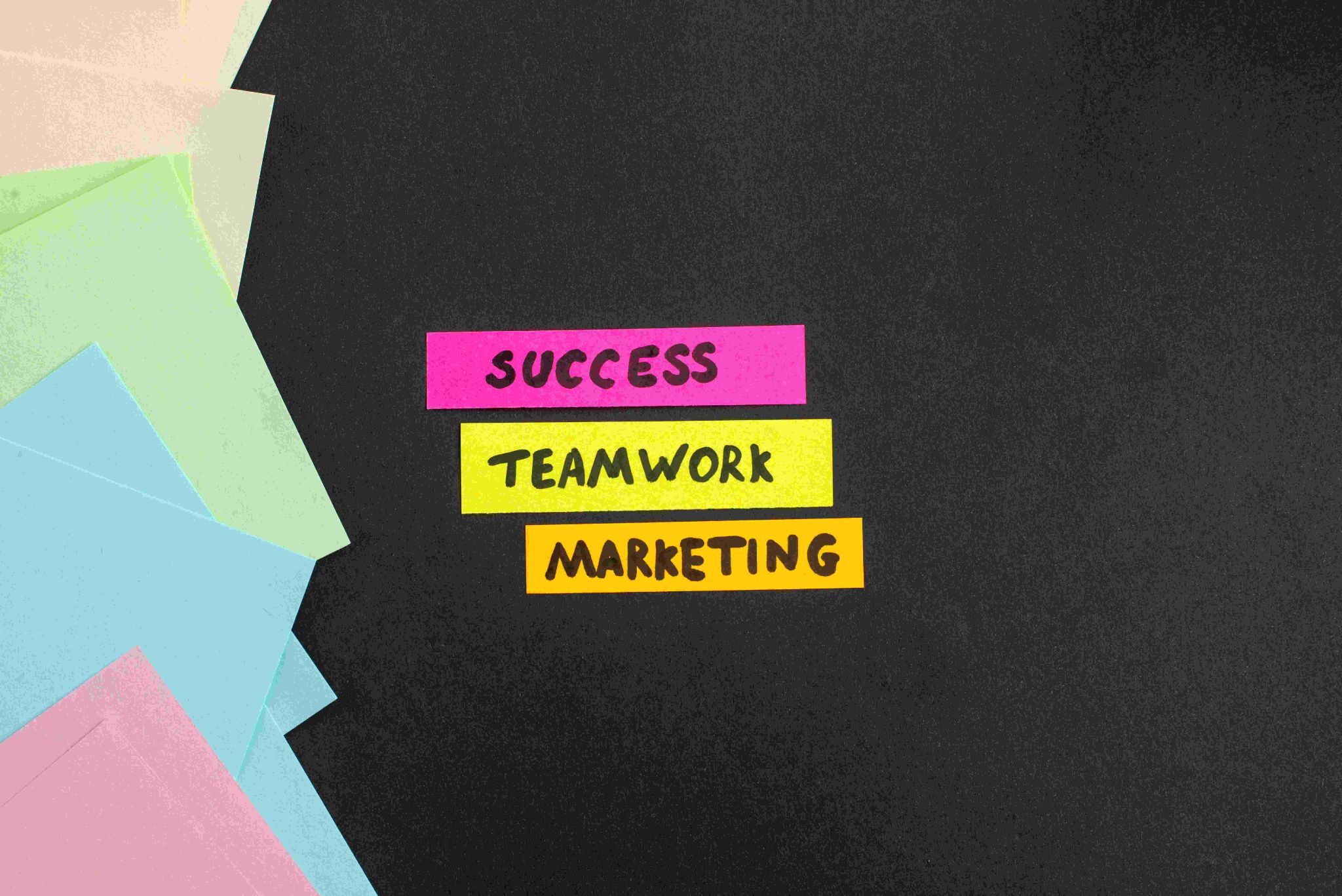 Sticky notes with "SUCCESS," "TEAMWORK," and "MARKETING" on a dark background