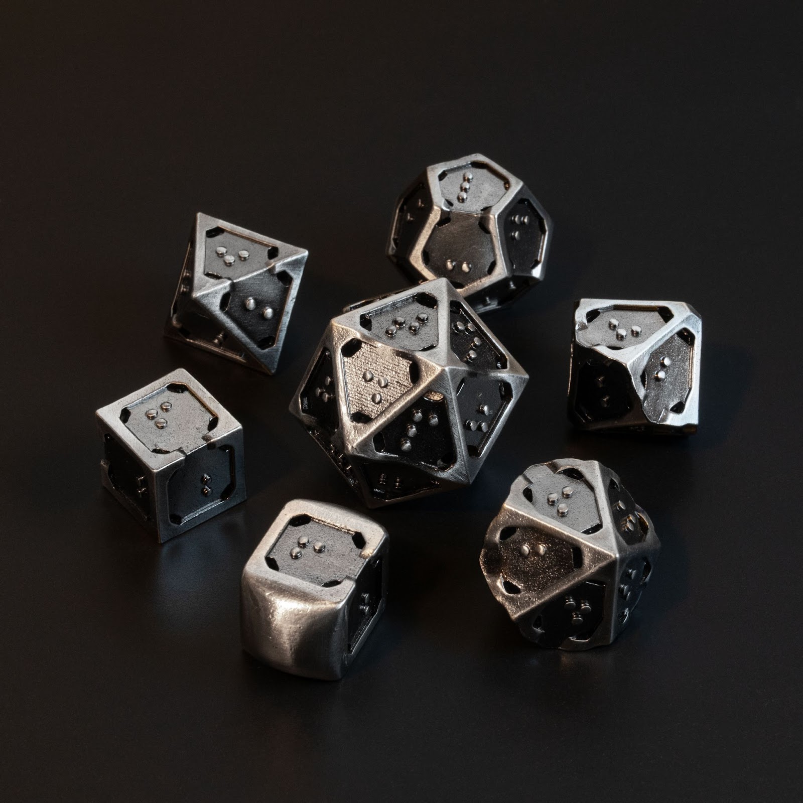 Photograph of hollow metal braille d4, d6, d8, d10, d12 surrounding a d20. 