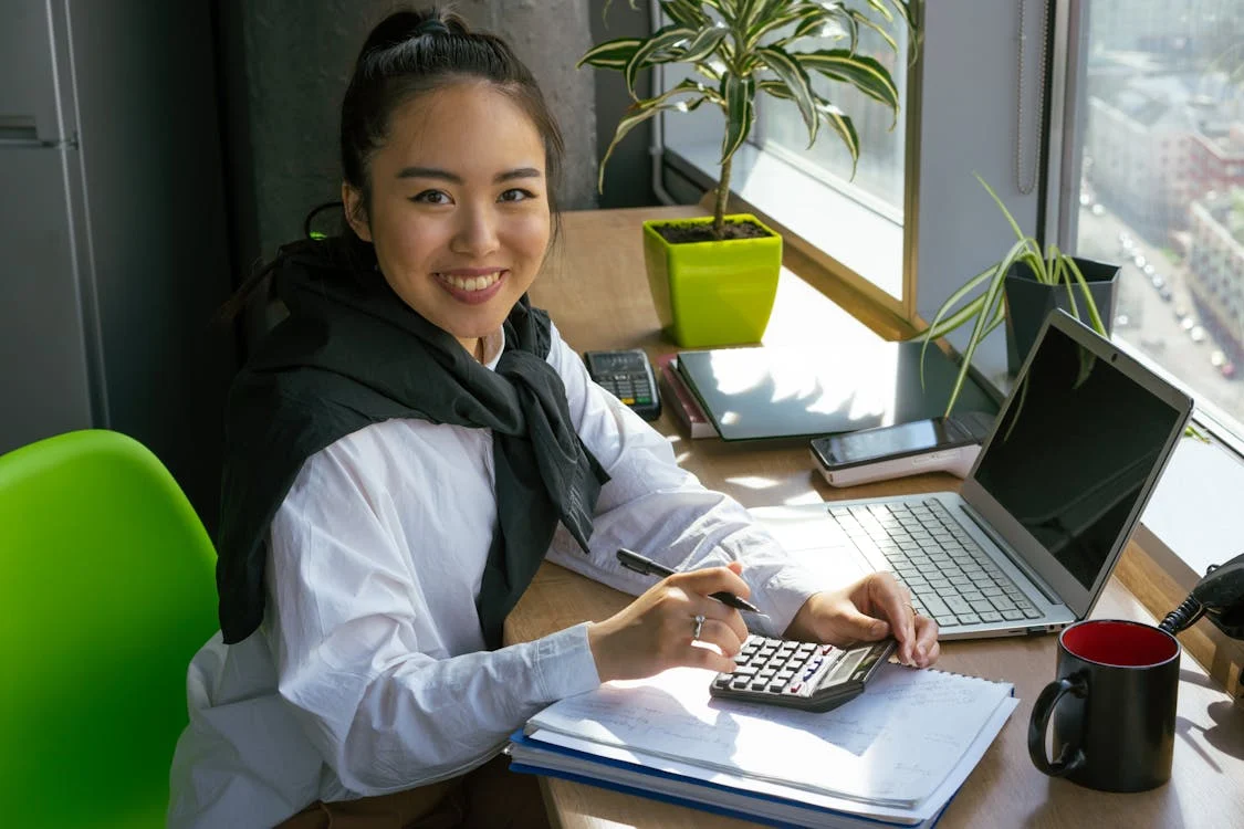 woman in white dress shirt using calculator
