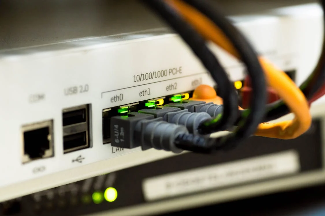 Close-up of an Ethernet switch or router with multiple Ethernet cables connected to ports labeled eth0, eth1, and eth2, with green indicator lights signifying active connections