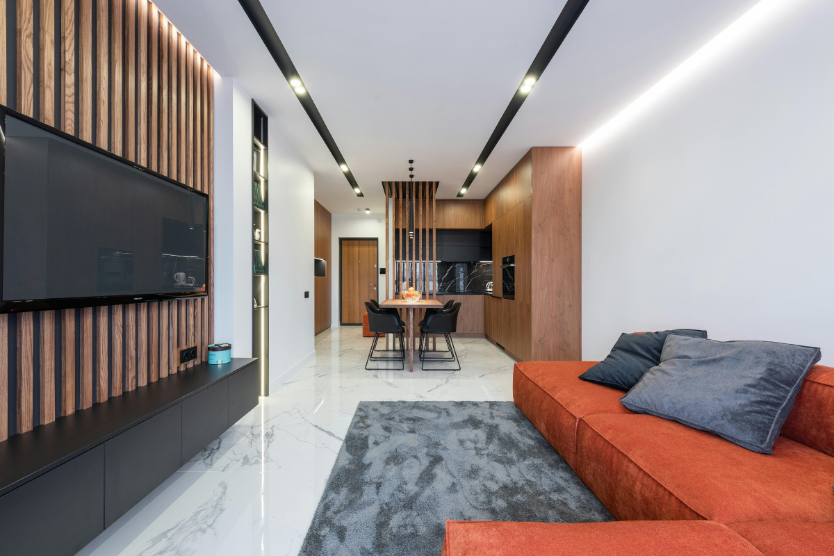 Living room featuring fluted wall panel, vibrant orange couch, and mounted wall light for stylish accent lighting.