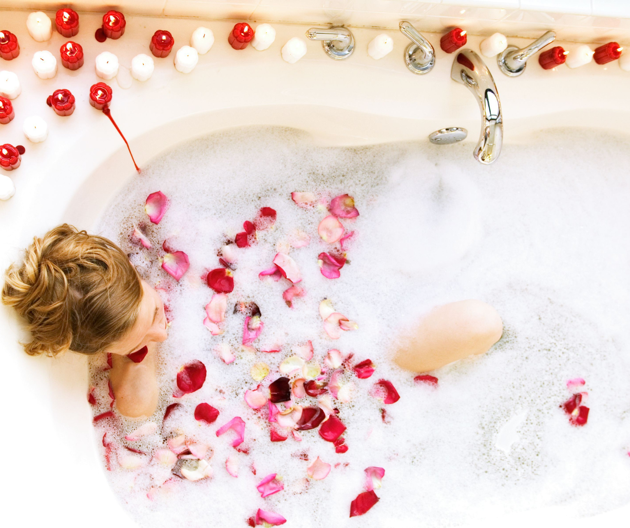 A woman in a bath with rose petals