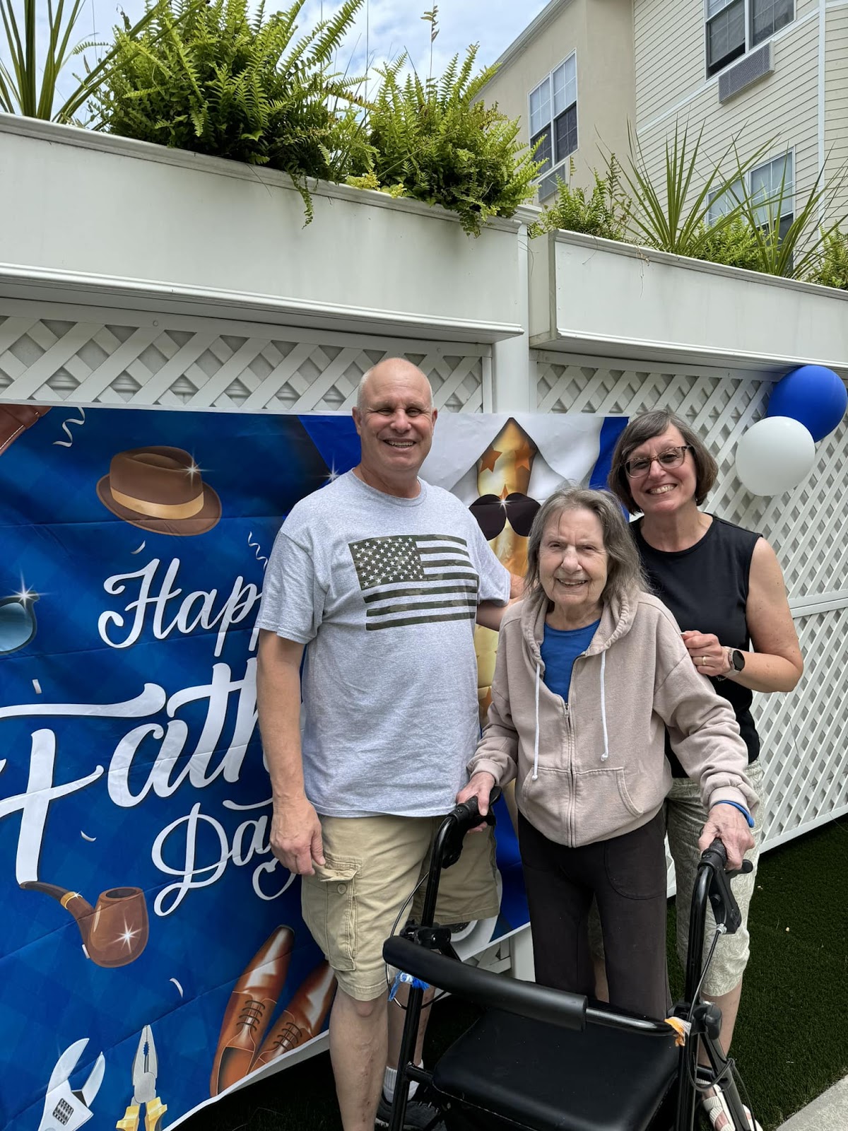 A woman smiling with her family behind her next to a Father's Day sign