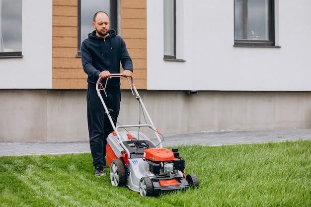 Man cutting grass with lawn mover in the back yard