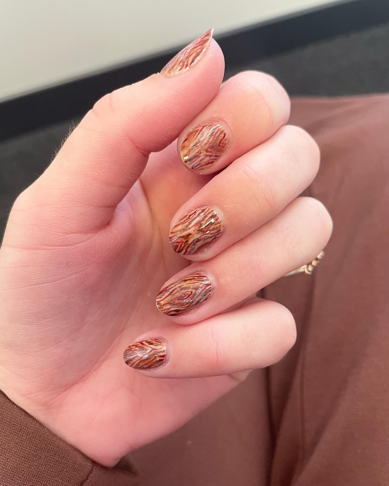 Close-up of hands with fall nail design having Wood Grain Effects