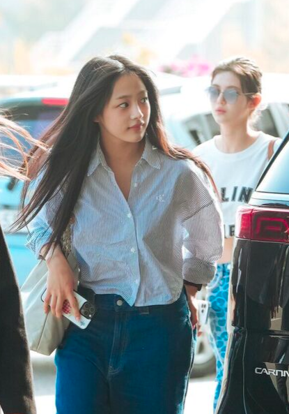 This contains an image of Minji on a crisp pinstripe shirt with well-fitted jeans