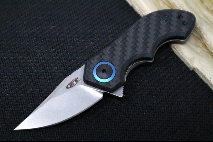 An image showing the Zero Tolerance 0022, a small folding knife with full titanium handles, on a solid black and wood background.