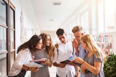 This contains a group of people standing around each other looking at something on a clipboard 