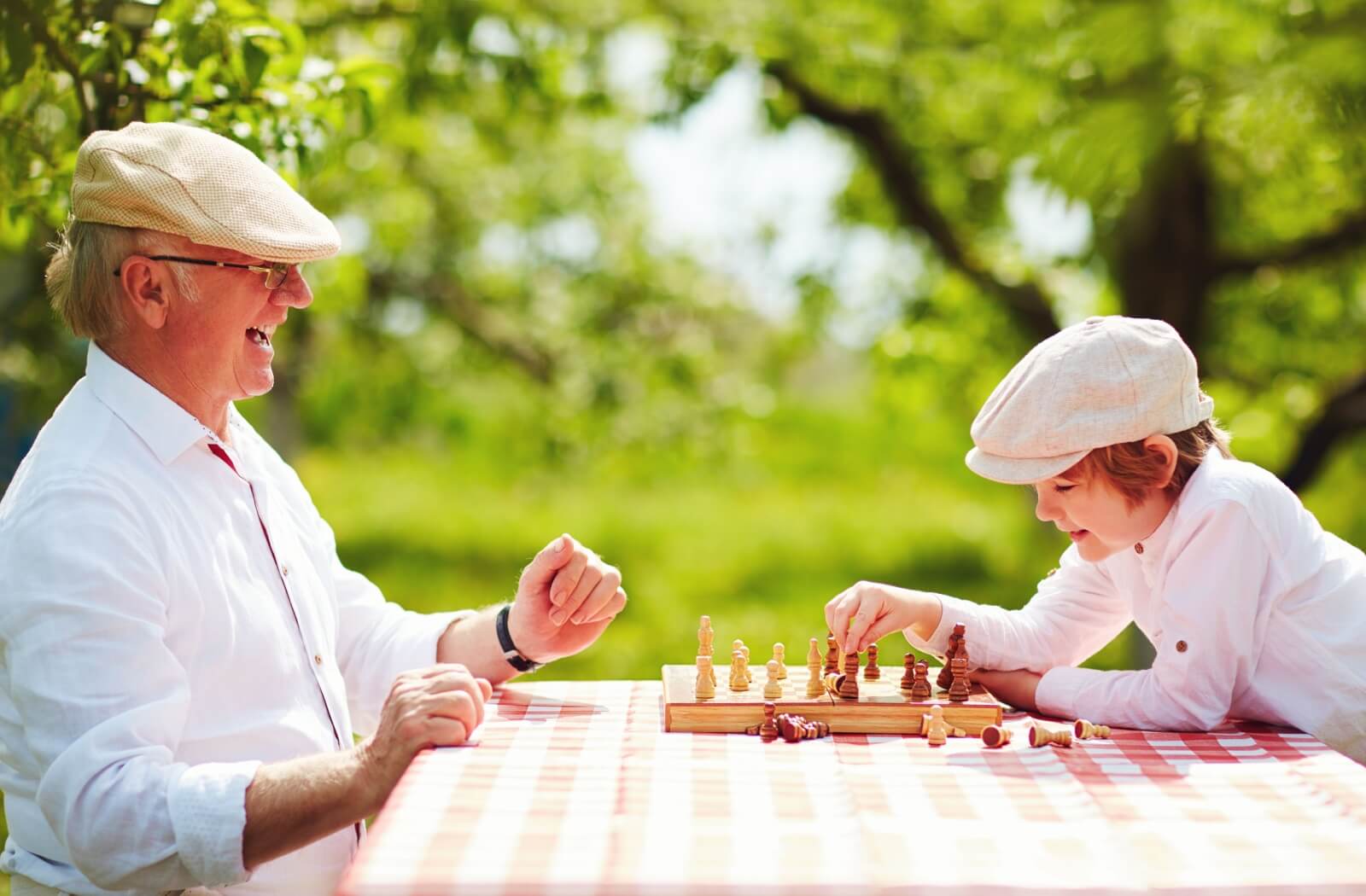 A happy senior plays a lively game of chess with their grandchild.