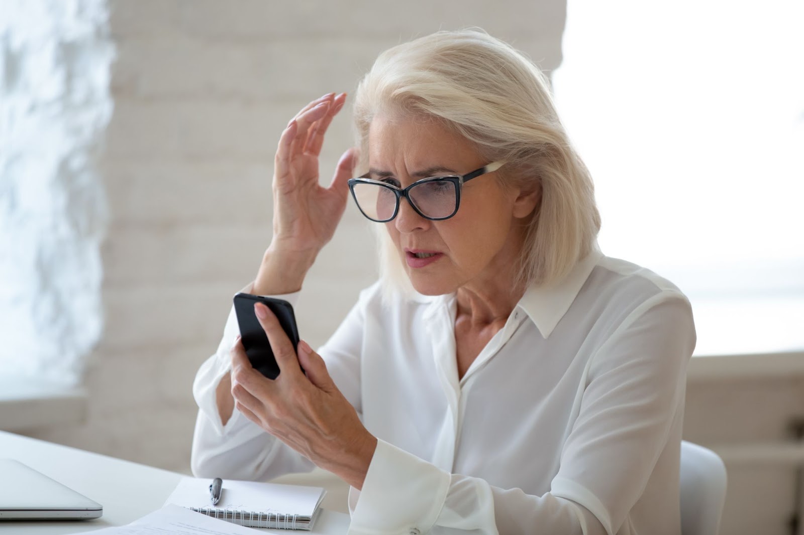 Senior woman looking frustrated as she tries to figure out something on her phone.