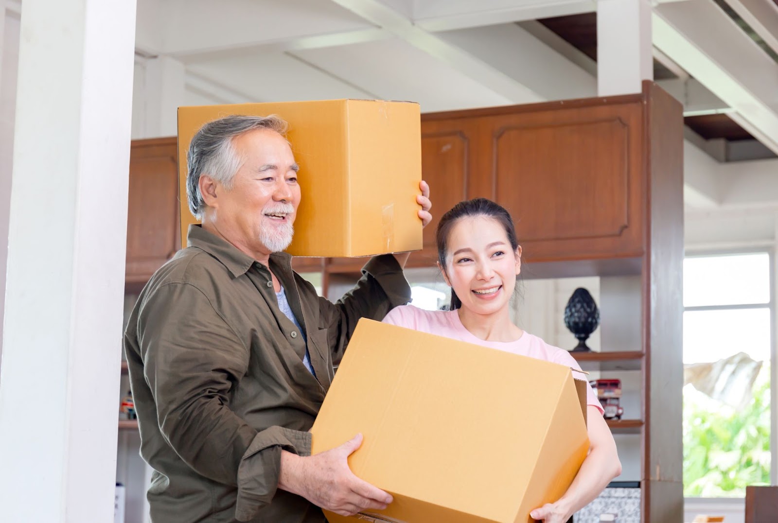 A woman helps her senior father move boxes into his new assisted living community.