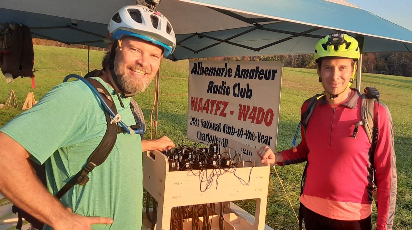 Two men standing next to a sign  Description automatically generated