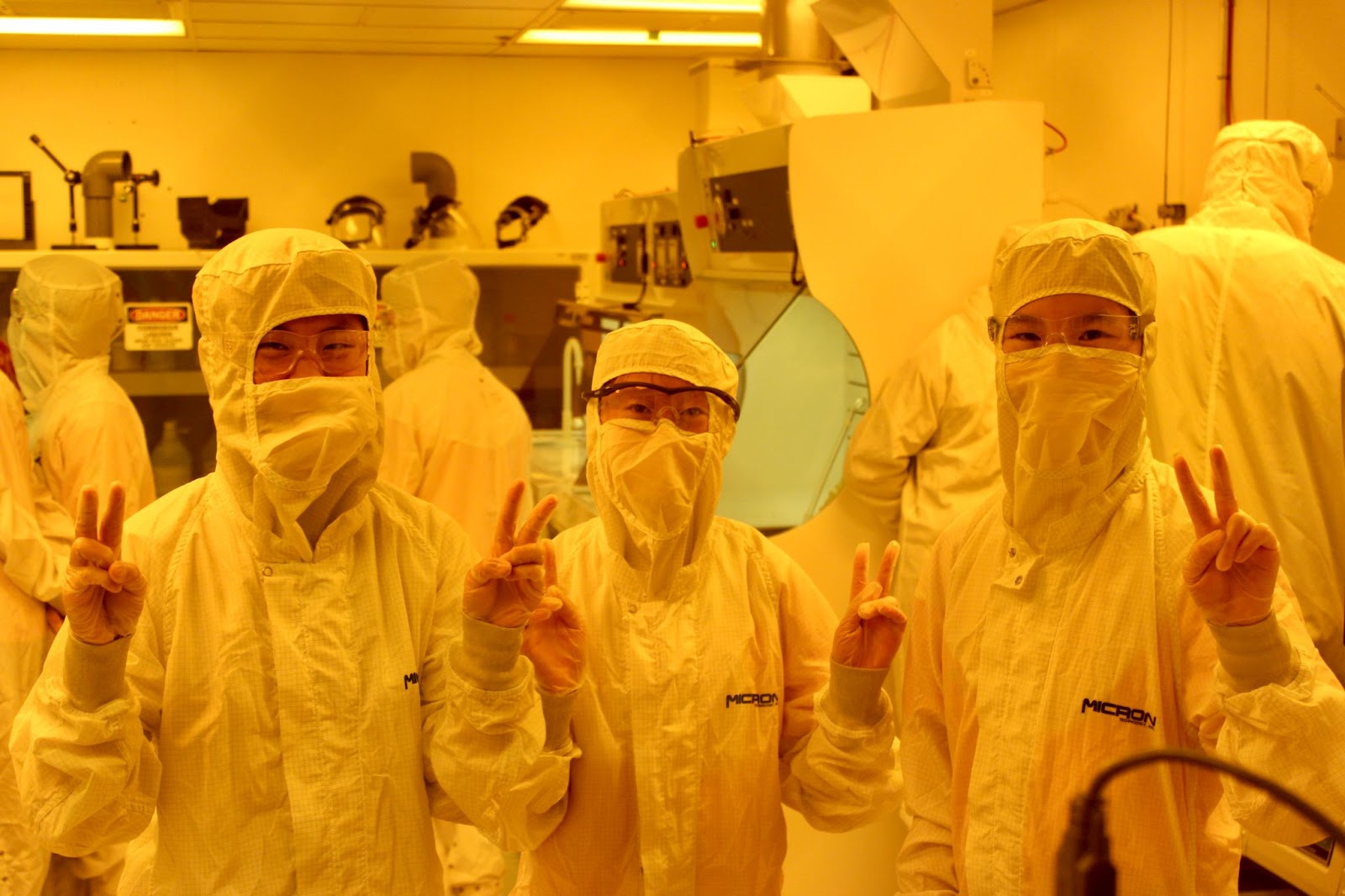 Image of three students in bunny suits giving a "peace sign" in the Boise State IML cleanroom