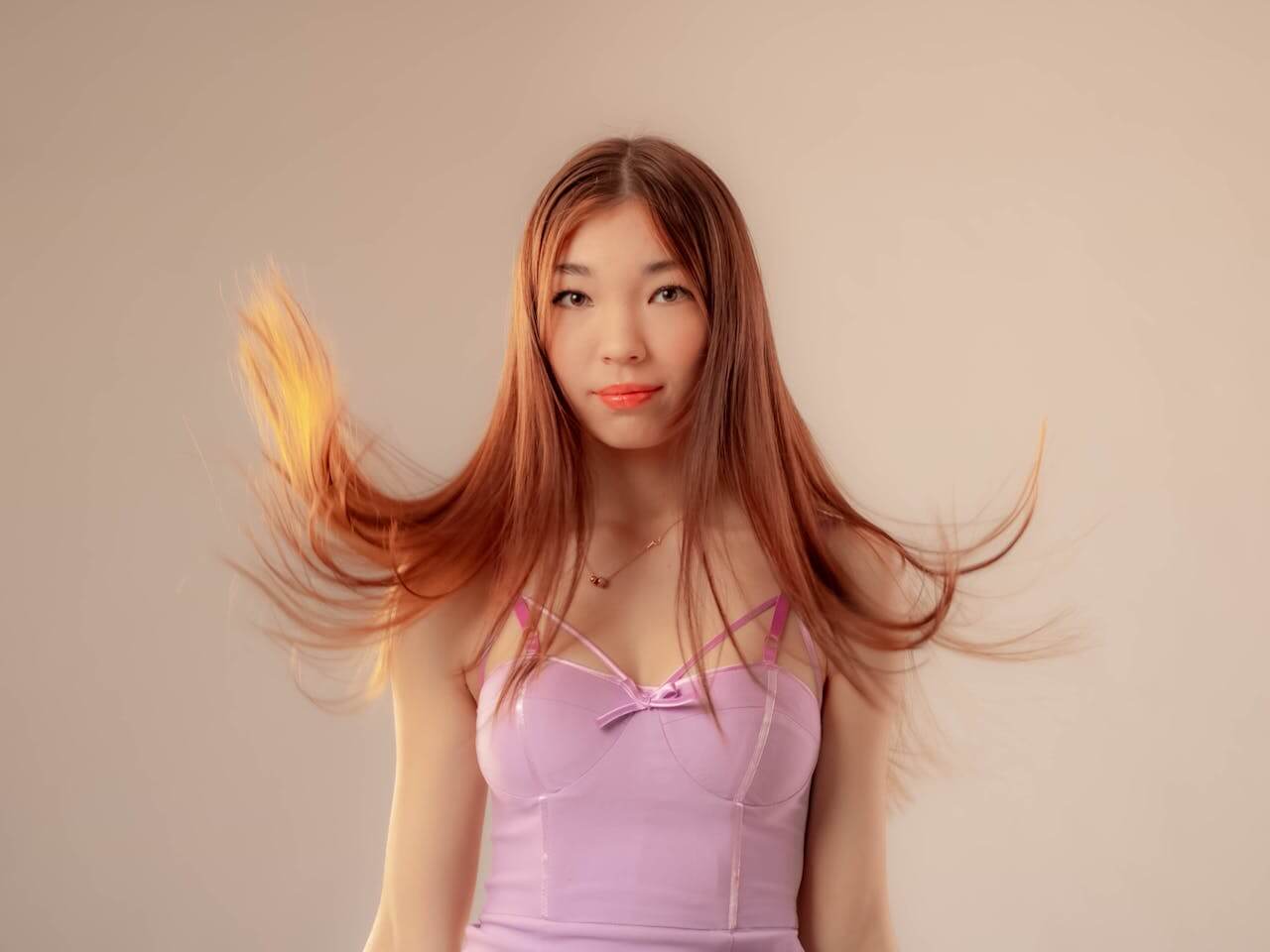 Asian woman with long hair in a purple dress, showcasing the benefits of herbal hair dye over chemical alternatives.