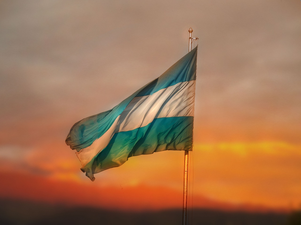 Bandera de Argentina ondeando al atardecer, símbolo de la independencia y el espíritu nacional argentino.
