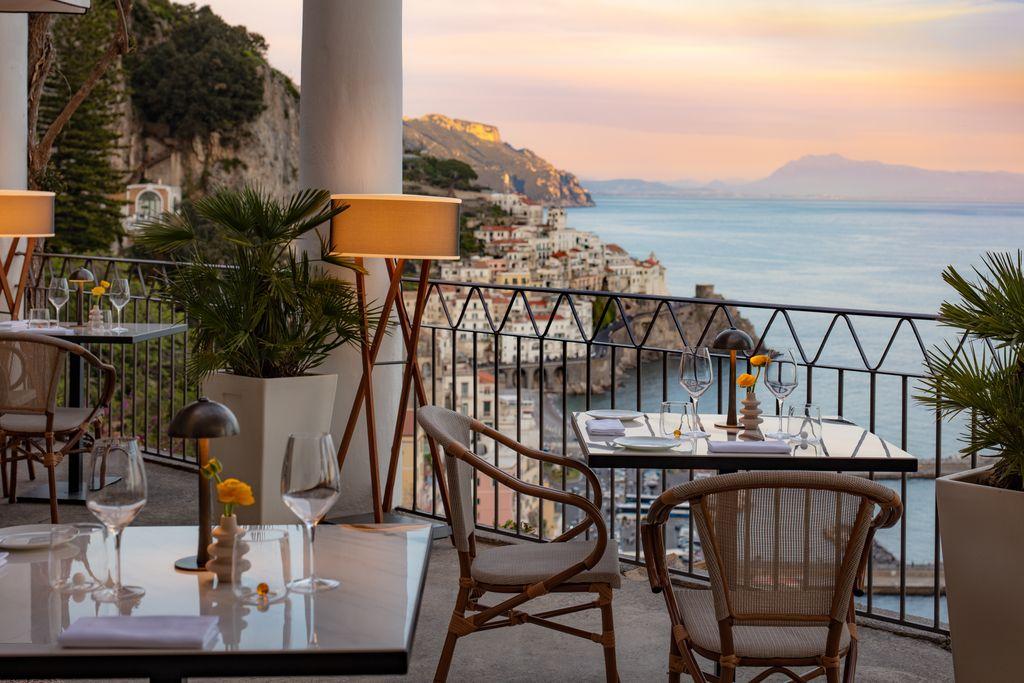 A table and chairs on a balcony overlooking a body of water

Description automatically generated